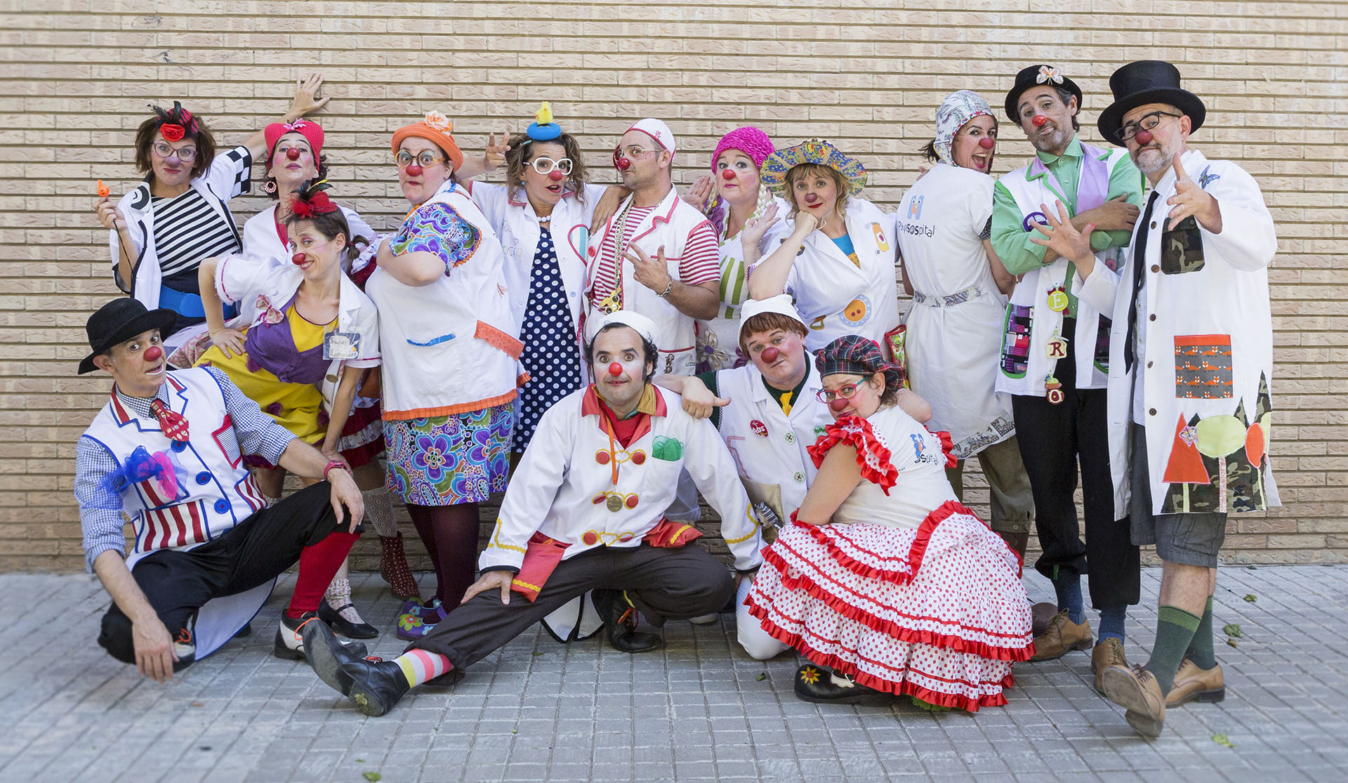 Equipo artístico de Payasospital posando en la acera frente a pared de ladrillos claros