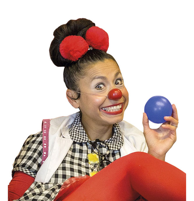 Plano medio de una payasa con una gran sonrisa que sostiene una pelota azul en la mano